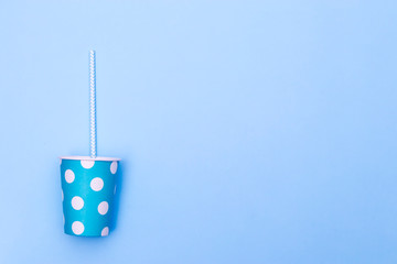 Blue paper cup in dot for cocktails with a straw isolated on background. Copy space
