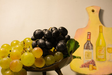  White and blue grapes in a vase on the background of decorative boards