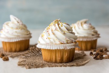 Closeup of a cupcake with white frosting and sprinkles on a white surface