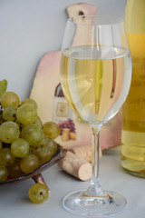 White grapes and wine from it in a glass and a bottle on the background of a decorative board