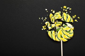 Broken lollipop candy on black background