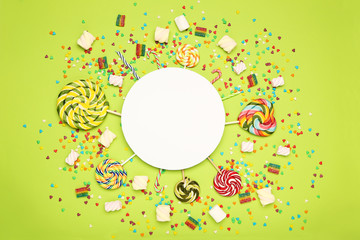 Colorful flat lay composition with various candies on green background