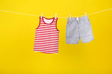 Baby clothes hanging on yellow background