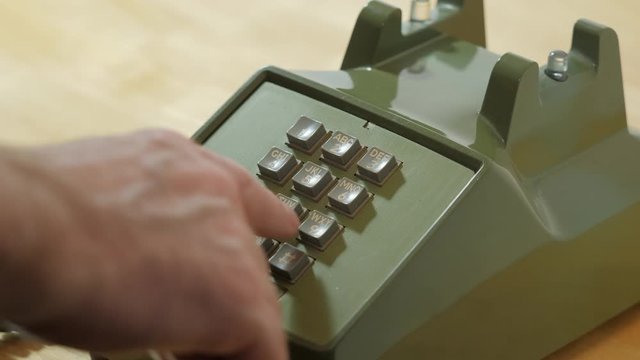 Man dialing retro push button rotary dial telephone. Making phone call on vintage avocado green landline phone.