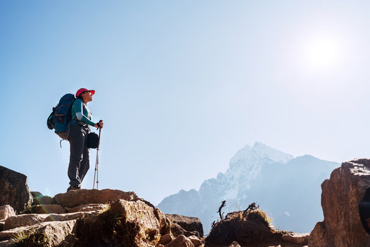 Young hiker backpacker female on cliff edge enjoying the Thamserku 6608m mountain during high altitude Acclimatization walk. Everest Base Camp trekking route, Nepal. Active vacations concept image