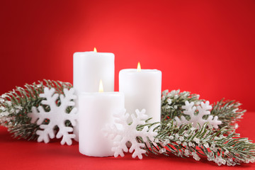 Fototapeta na wymiar Christmas candles with snowflakes and fir tree branches on red background