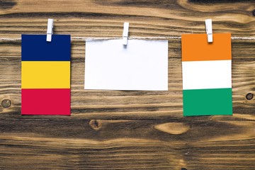 Hanging flags of Chad and Cote D'Ivoire attached to rope with clothes pins with copy space on white...
