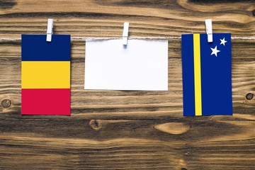Hanging flags of Chad and Curacao attached to rope with clothes pins with copy space on white note...
