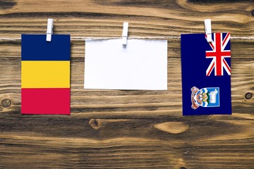 Hanging flags of Chad and Falkland Islands attached to rope with clothes pins with copy space on...