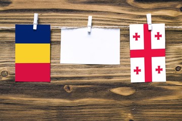 Hanging flags of Chad and Georgia attached to rope with clothes pins with copy space on white note...