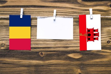Hanging flags of Chad and Gibraltar attached to rope with clothes pins with copy space on white...