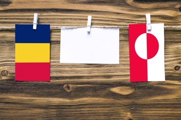 Hanging flags of Chad and Greenland attached to rope with clothes pins with copy space on white...