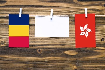 Hanging flags of Chad and Hong Kong attached to rope with clothes pins with copy space on white...