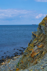 rock cliff edge in front of sea and blue sky