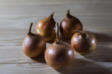 Fresh onions on wooden background. Yellow onions on a wooden table, closeup.