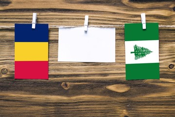 Hanging flags of Chad and Norfolk Island attached to rope with clothes pins with copy space on...