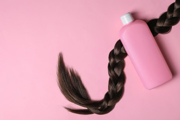 Blank bottle of cosmetic product and braided hair on pink background, flat lay. Space for design