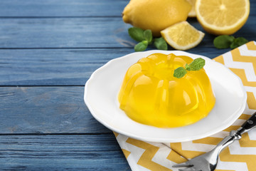 Plate with lemon jelly and mint served on blue wooden table. Space for text
