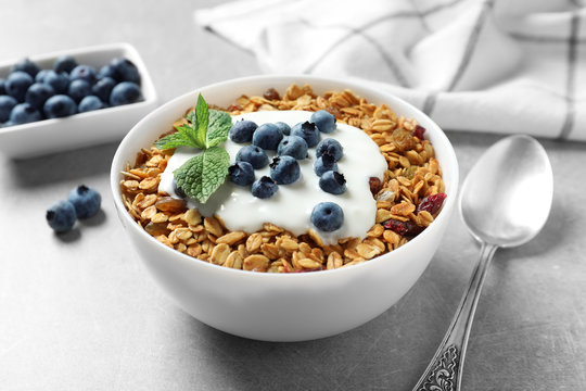 Delicious yogurt with granola and blueberries served on grey table