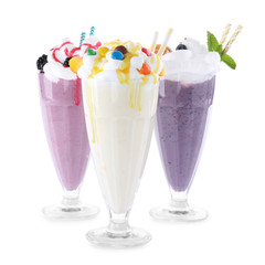 Different tasty milk shakes in glasses on white background