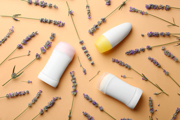 Different female deodorants and lavender flowers on apricot background, flat lay