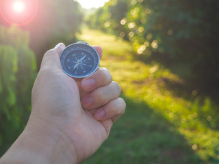 Hand holding navigate compass on street to find the target.