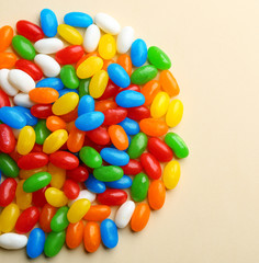 Pile of colorful jelly beans on beige background, flat lay. Space for text