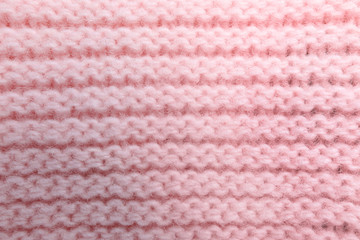 Pink knitted sweater as background, closeup view