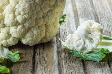 Fresh organic raw whole and piece cauliflower on wooden rustic background, healthy food vegetable...