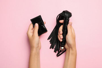 Woman with whip and condoms on pink background, top view. Sex game