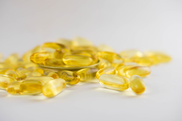 Omega 3 capsules lying in the lid on a white background. Scattered around.