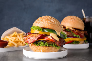 Composition with juicy bacon burger on grey table