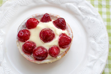 Cupcake with berries on a white round plate. Basket of shortcrust pastry with butter cream and strawberries. Sweet tasty pastries for tea. Desserts with berries and creamy jelly.