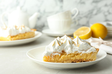 Plate with piece of delicious lemon meringue pie on light table