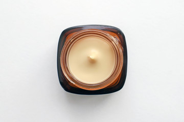 Jar with beige cosmetic cream. Glass jar of brown color on a white background. View from above. Square container with a round neck, without a lid.