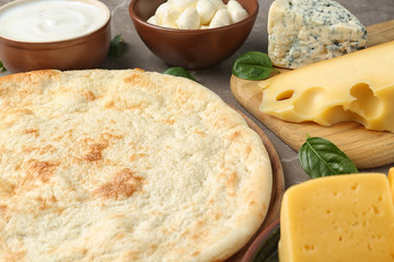 Pizza crust and fresh ingredients on table, closeup