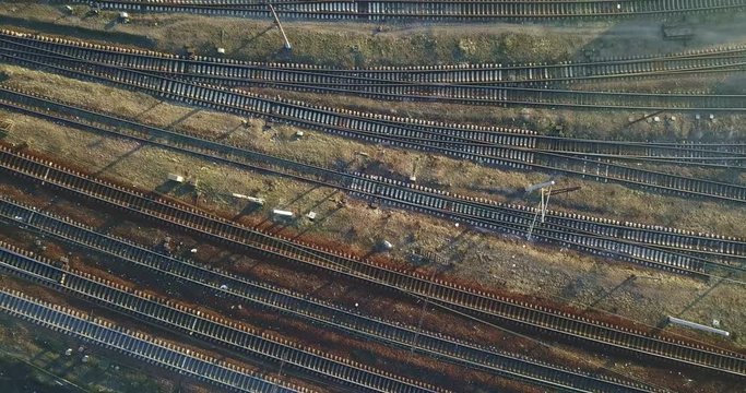 Lines of railway tracks with train cars, and a road with a passing car. 4K video, 240fps, 2160p.