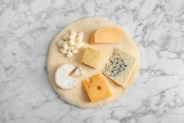Pizza crust with fresh ingredients on marble table, top view