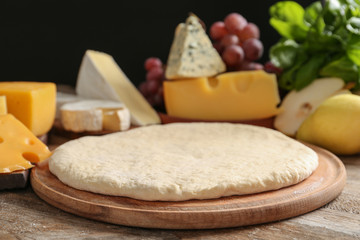 Pizza crust and fresh ingredients on wooden table, closeup