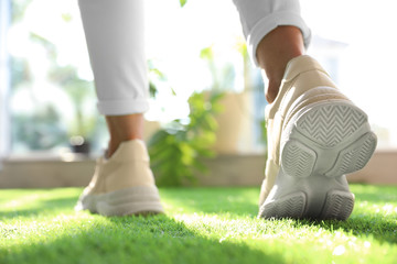 Young woman wearing stylish sneakers on green grass, closeup