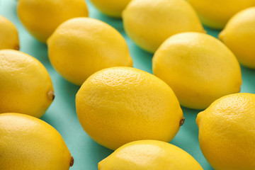 Many fresh lemons on turquoise background, closeup