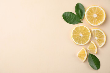 Fresh lemons and leaves on beige background, flat lay. Space for text