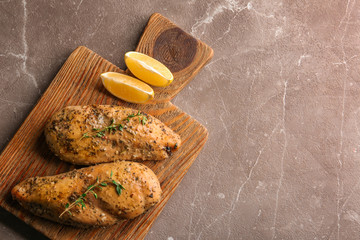 Baked lemon chicken with thyme served on grey marble table, top view. Space for text