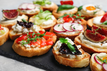 Different bruschettas on light grey marble table, closeup