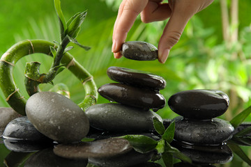 Woman stacking stones against blurred background, closeup. Zen concept