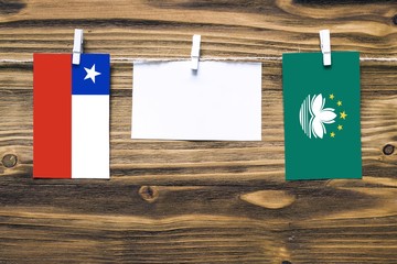 Hanging flags of Chile and Macao attached to rope with clothes pins with copy space on white note...