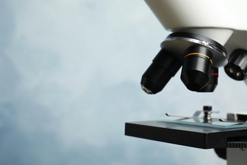 Closeup view of modern microscope on blue background, space for text. Medical equipment