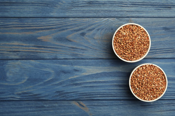 Buckwheat grains on blue wooden table, flat lay. Space for text
