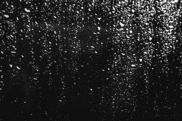 Naklejka na ściany i meble Glass with rain drops on black background