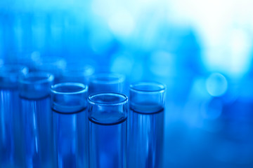 Test tubes with blue liquid on blurred background, closeup. Laboratory analysis